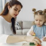 Mama i córka bawią się edukacyjnymi zabawkami przy stole w domu