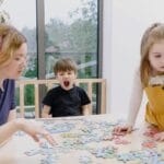 Rodzina układa puzzle przy stole w domu