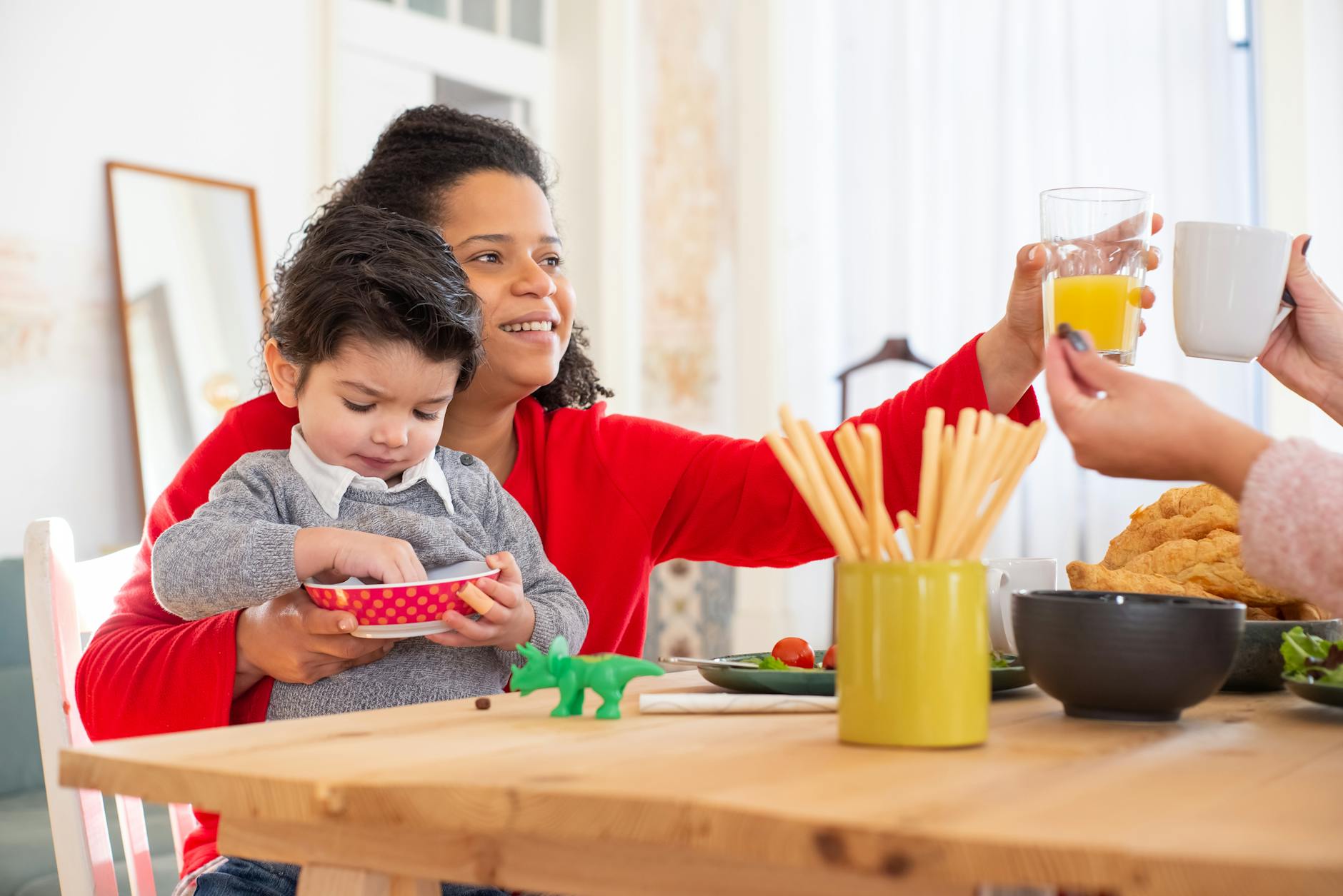 Rodzina z przedszkolakiem pije sok pomarańczowy przy śniadaniu