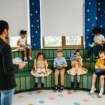 Nauczycielka czyta książkę grupie przedszkolaków w kolorowej sali