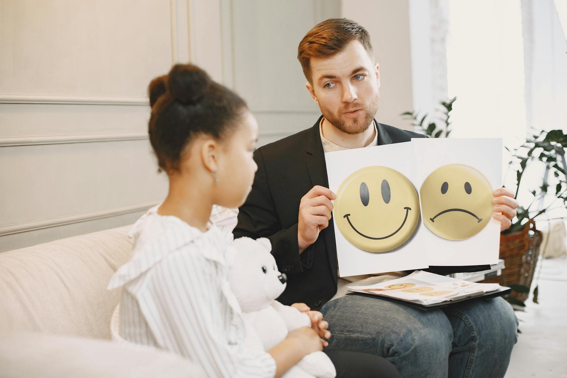 Logopeda z dzieckiem używają karty emocji podczas zajęć terapeutycznych