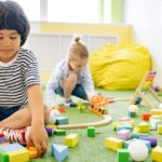 Dzieci bawiące się klockami i zabawkami w jasnej sali przedszkolnej