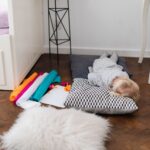 Małe dziecko śpi na poduszkach obok kolorowych zrolowanych materiałów