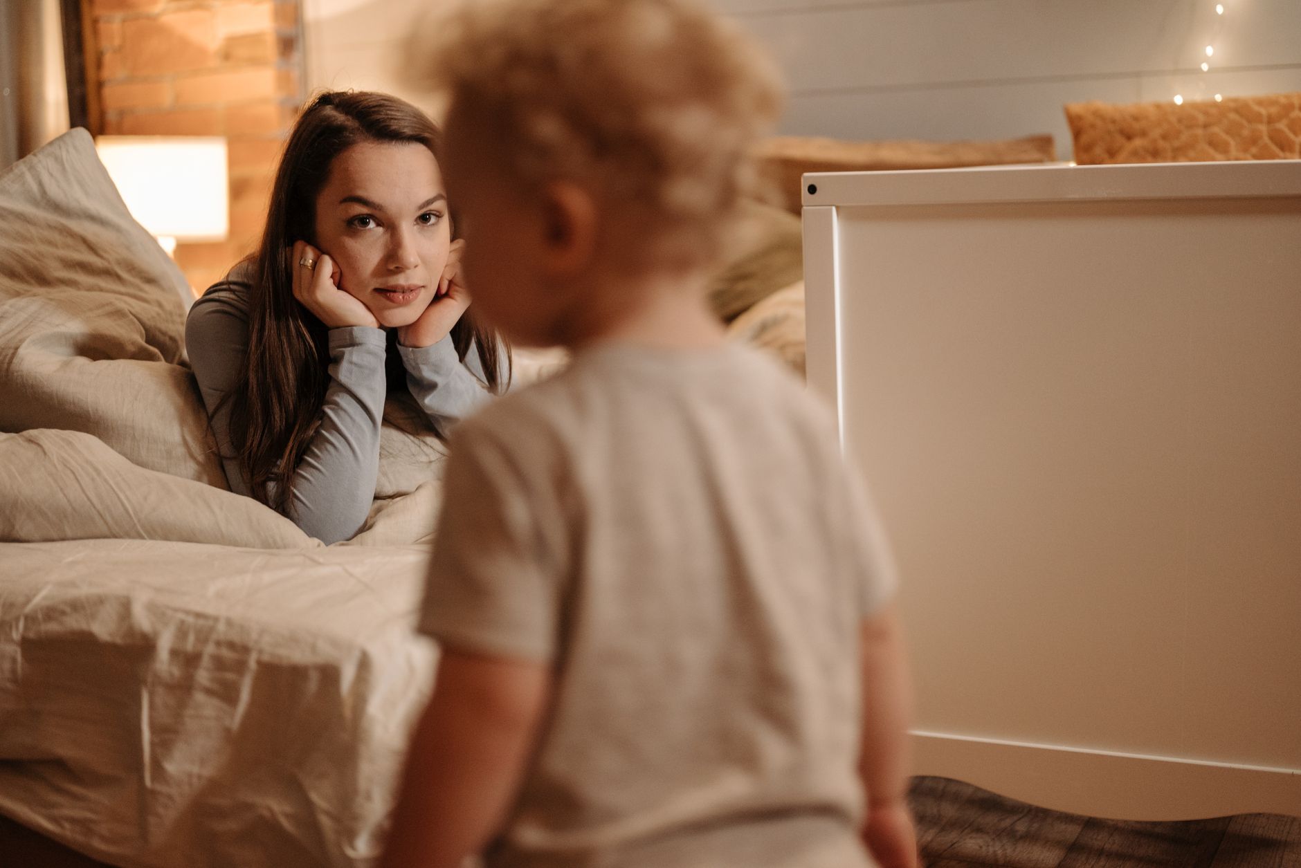 Mama przytula małe dziecko w ciepło oświetlonej sypialni
